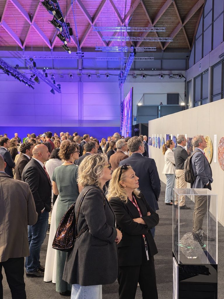 Visitatori e pubblico affascinati dalle opere esposte sulla parete durante la mostra al BEX di Rimini.