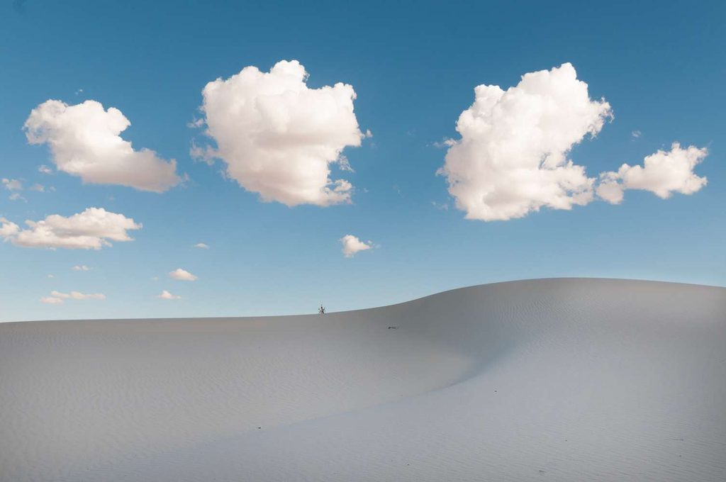 Paesaggio desertico astratto: Vista di un vasto deserto con dune ondulate che creano un motivo astratto e grafico, che si estende all'orizzonte.