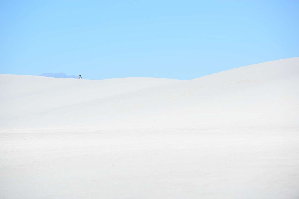 Dune bianche e cielo: Una veduta panoramica di dune di sabbia bianca brillante che contrastano con un cielo azzurro limpido e senza nuvole.