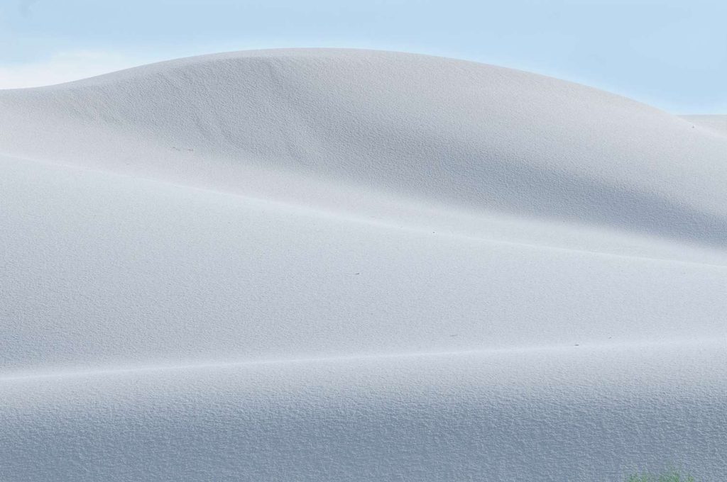 Forme e texture delle dune: Uno scatto ravvicinato che enfatizza la texture fine della sabbia e le forme sinuose e fluide delle dune, in una composizione naturalistica.