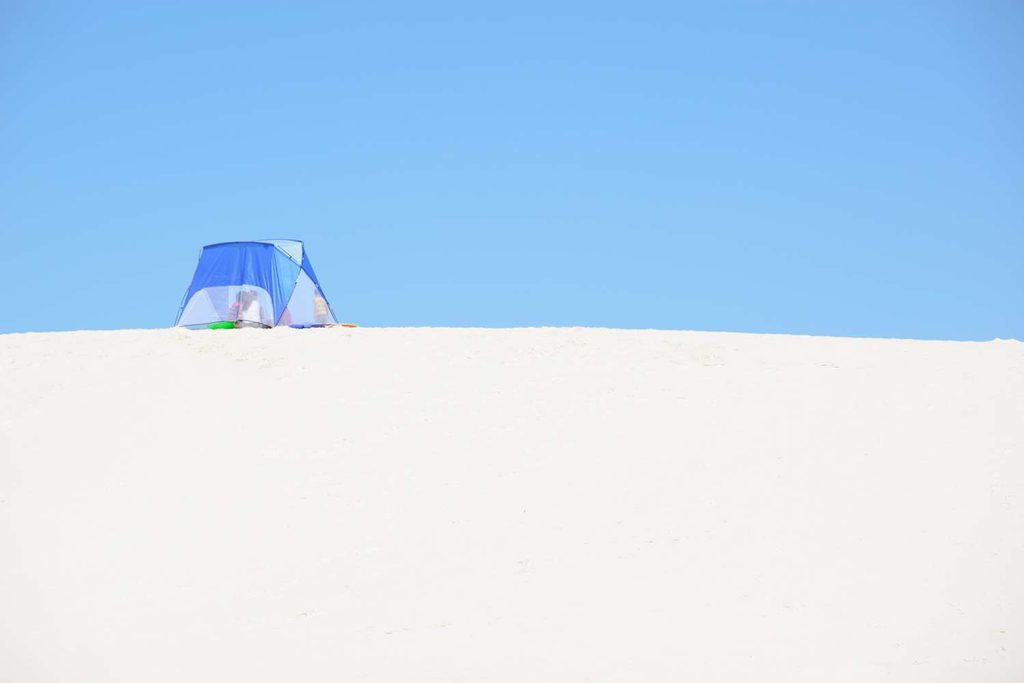 Duna di sabbia bianca con tenda e turista.